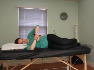 Shoulder internal rotation stretch while lying on the injured side to stabilize the scapula