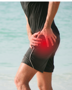 Person in athletic shorts holding their hip with redness at hip indicating pain.